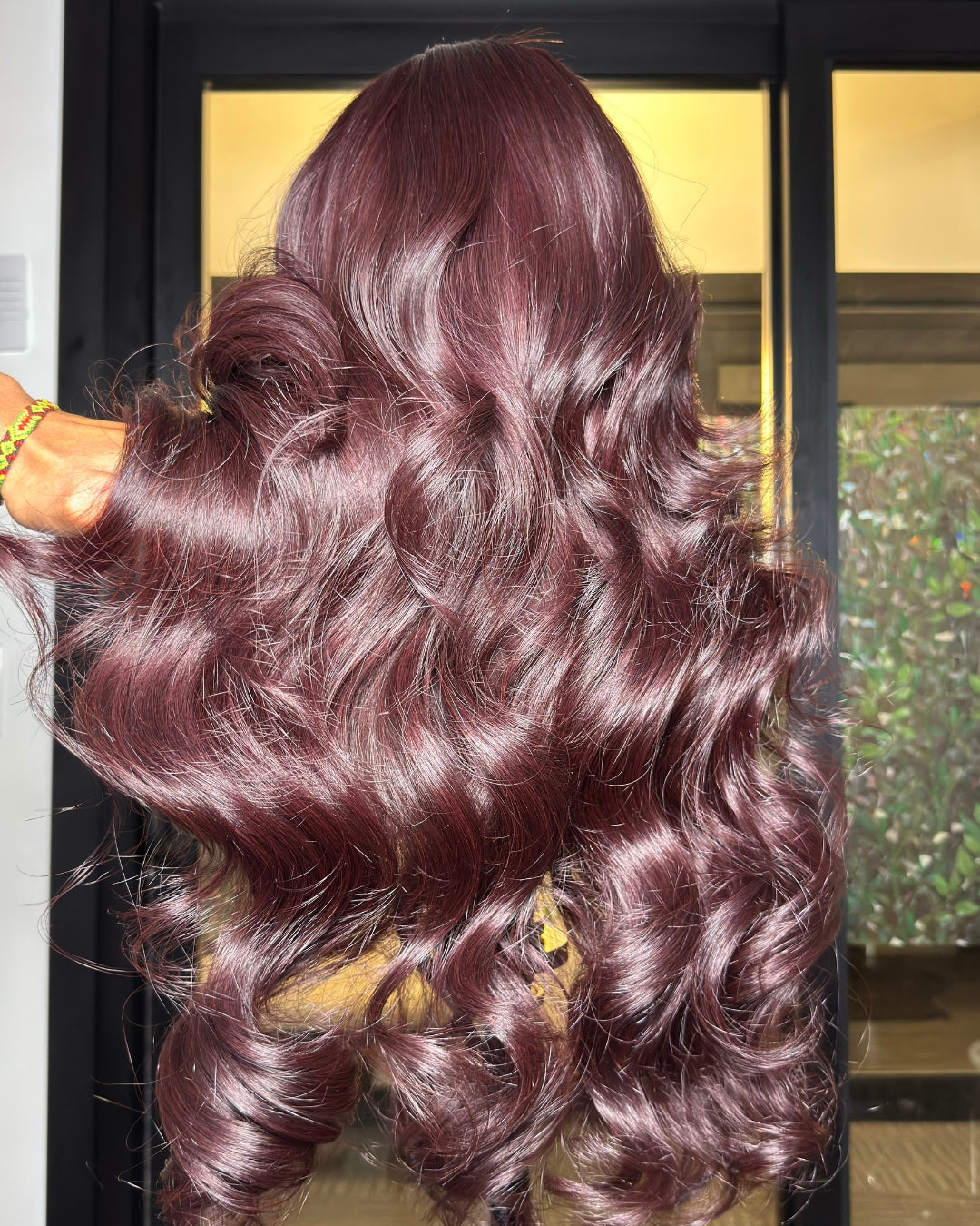 Burgundy hair extensions styled in loose curls on a mannequin head.